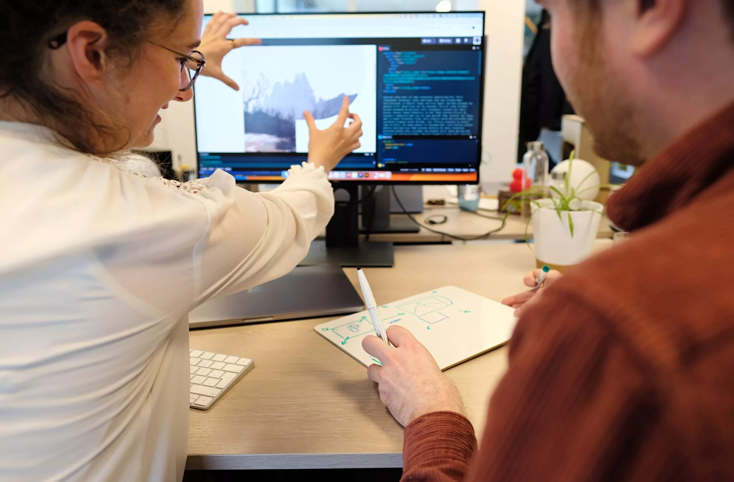 Deux personnes devant un écran : l'une imite un mouvement d'un visuel avec les mains, l'autre décortique ce mouvement en dessin.